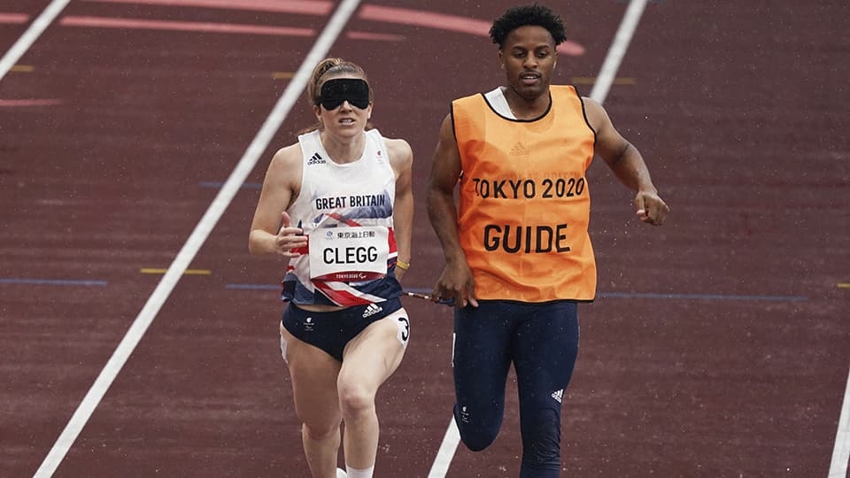 Female visually impaired runner with guide in Tokyo 2020 Paralympics race.
